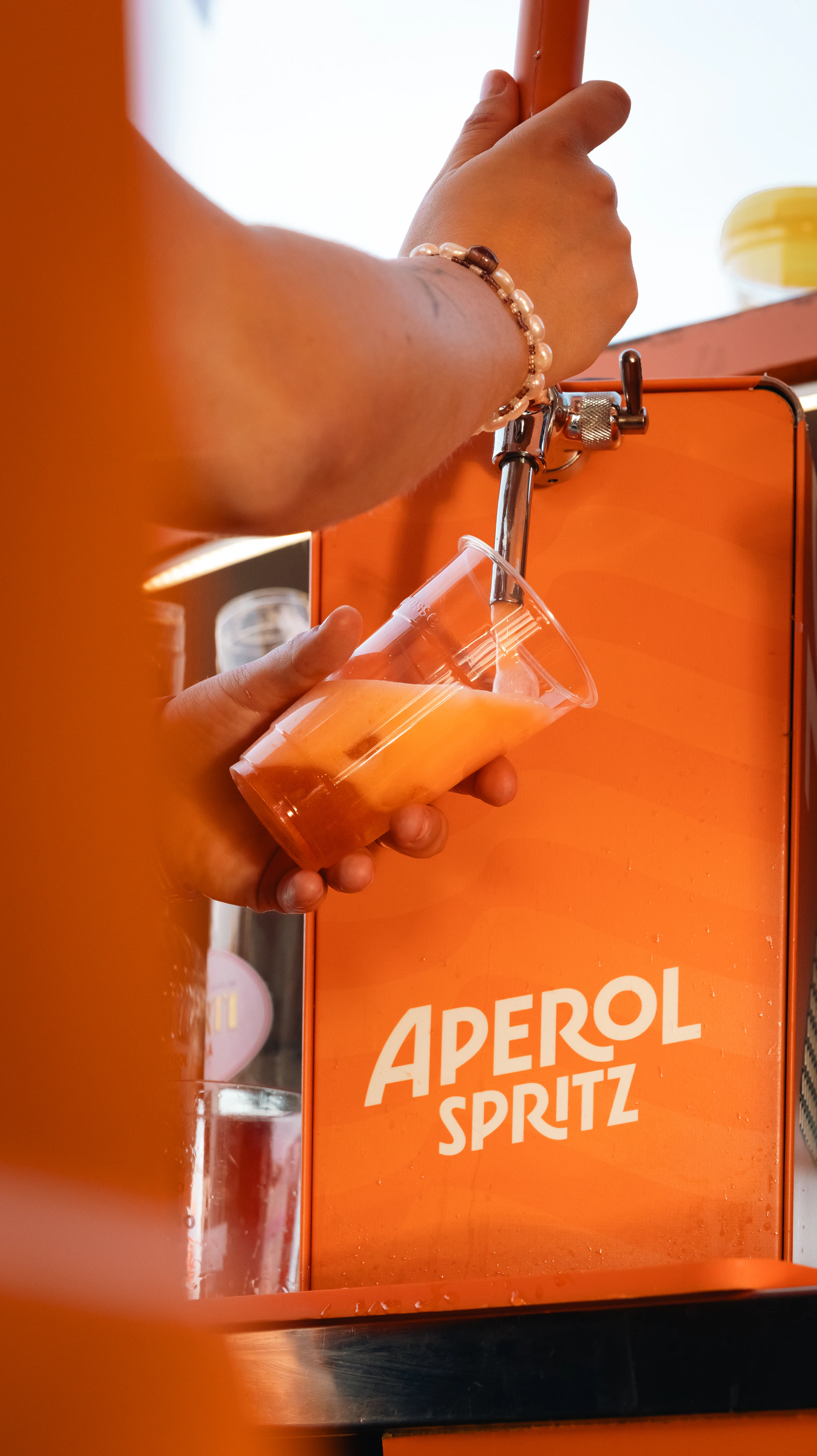 A hand taking a spritz at the Aperol counter