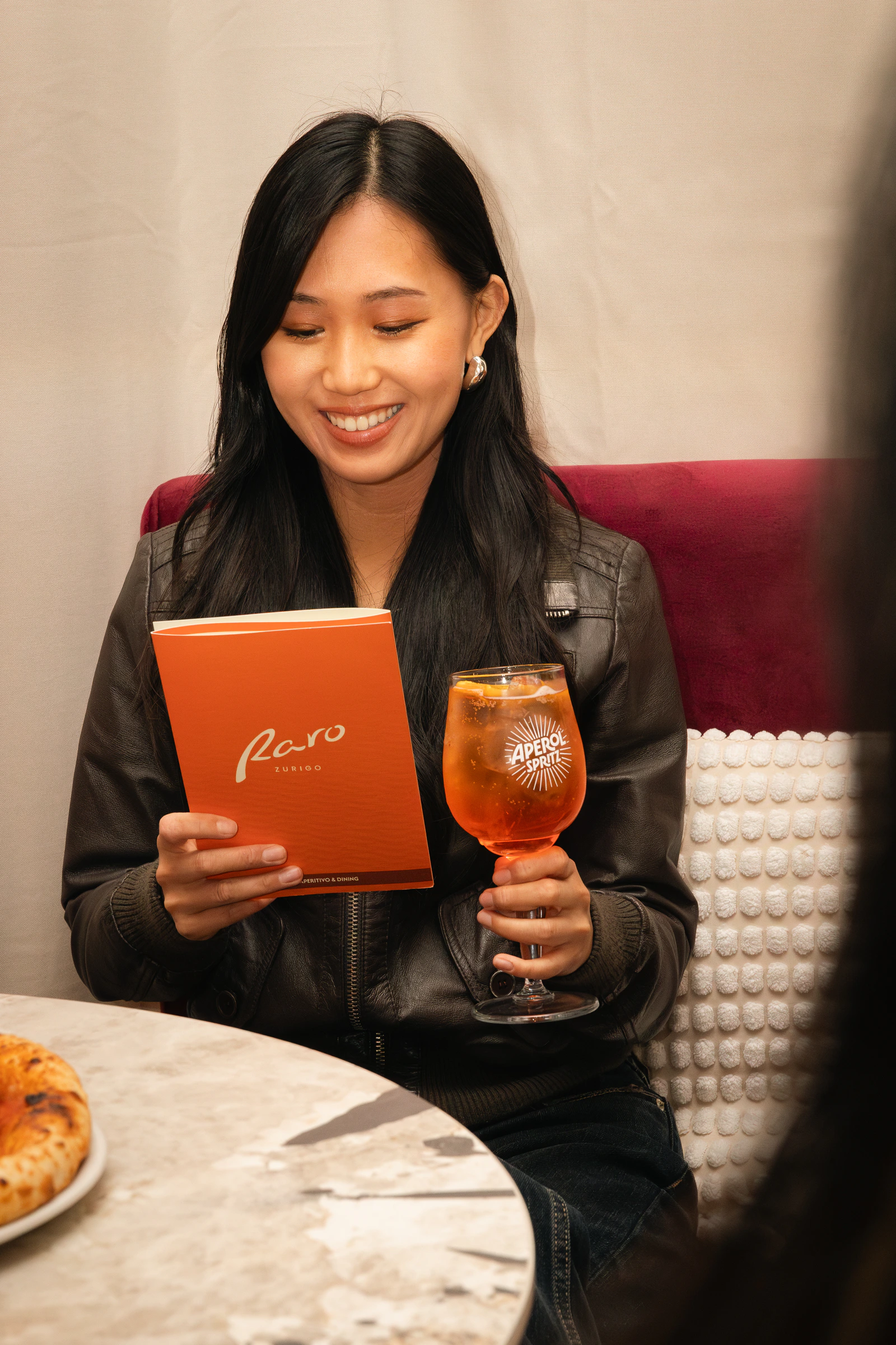 A guest reading the menu in a booth, spritz in hand