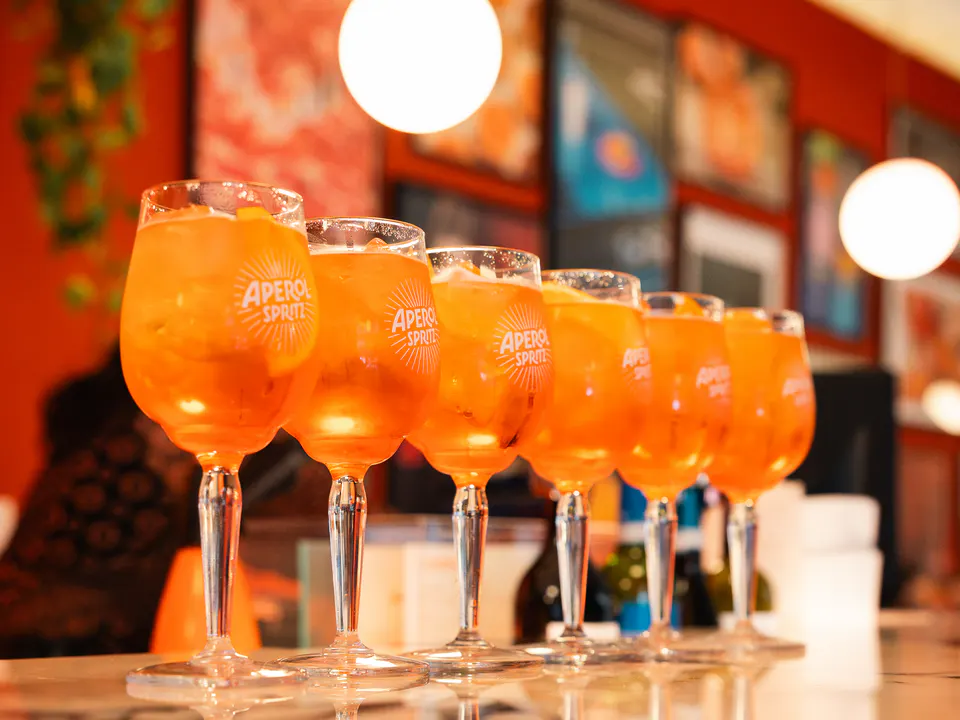 A row of Aperol Spritz lined up on the bar, ready to go out