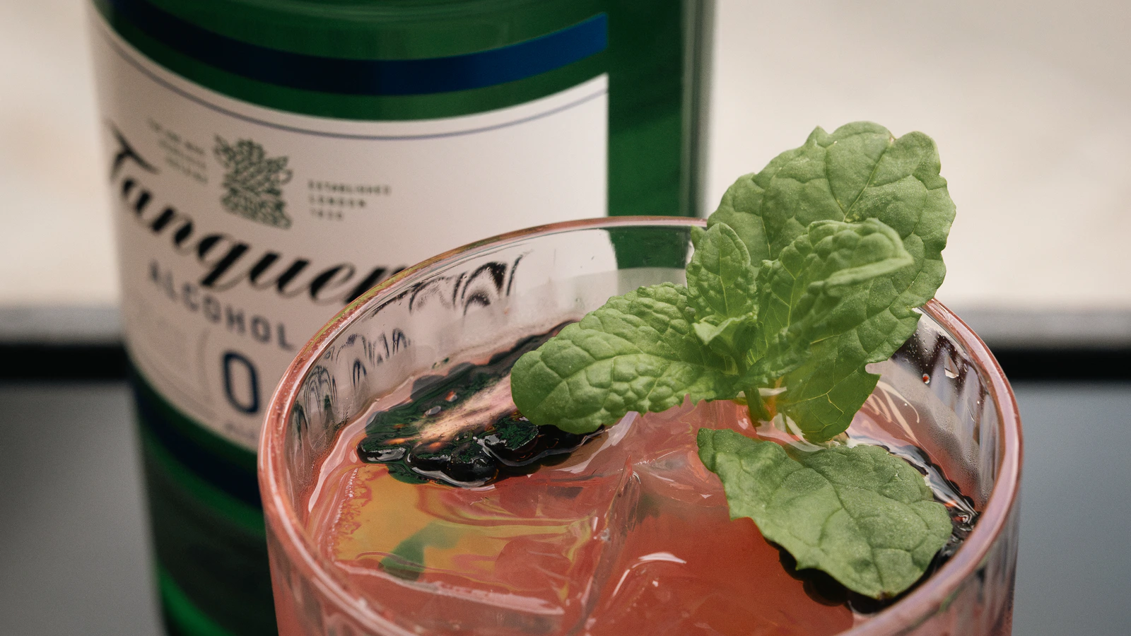 A cocktail beside a gin bottle, shot close
