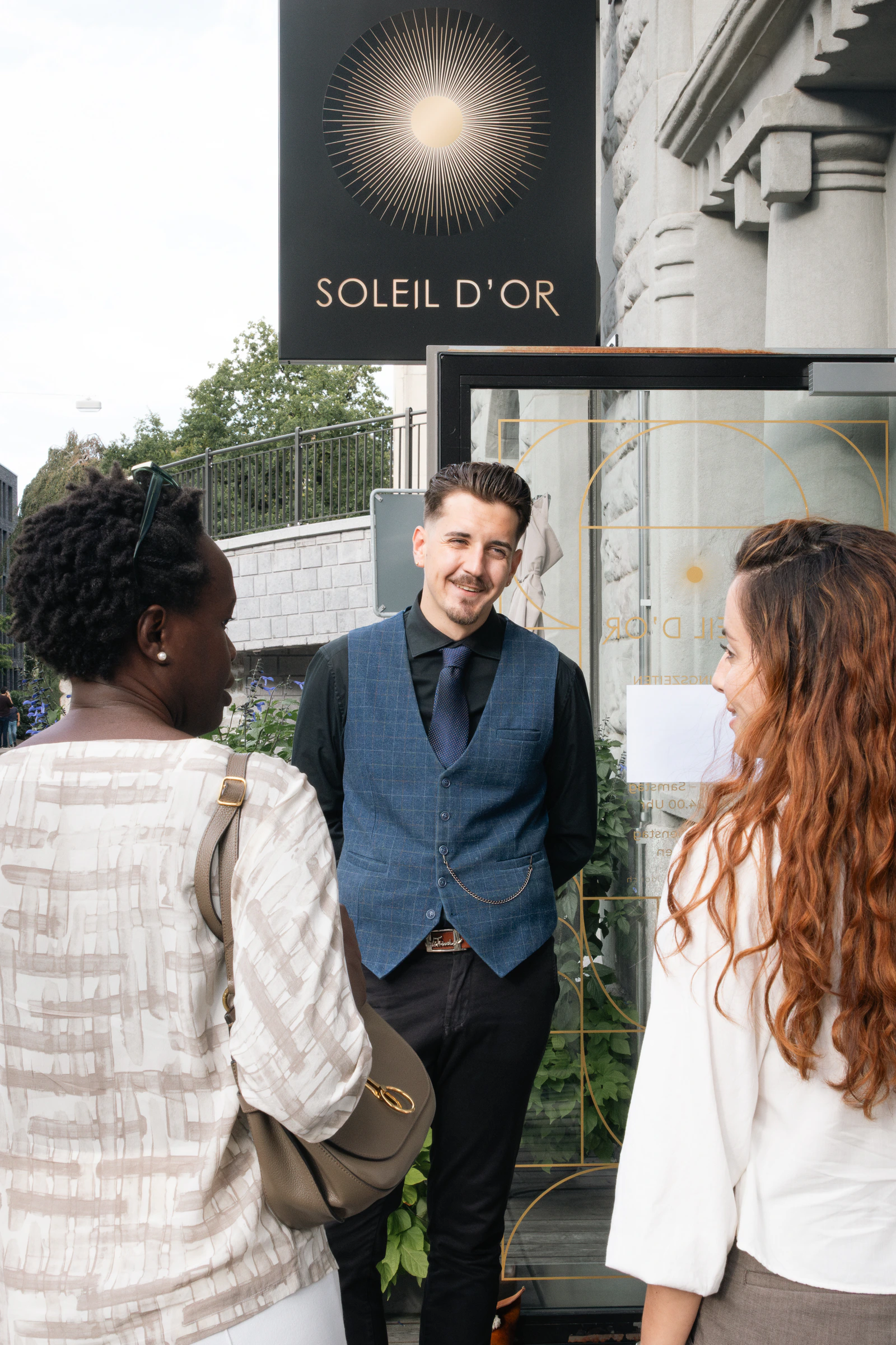 Guests talking on the pavement under the sign