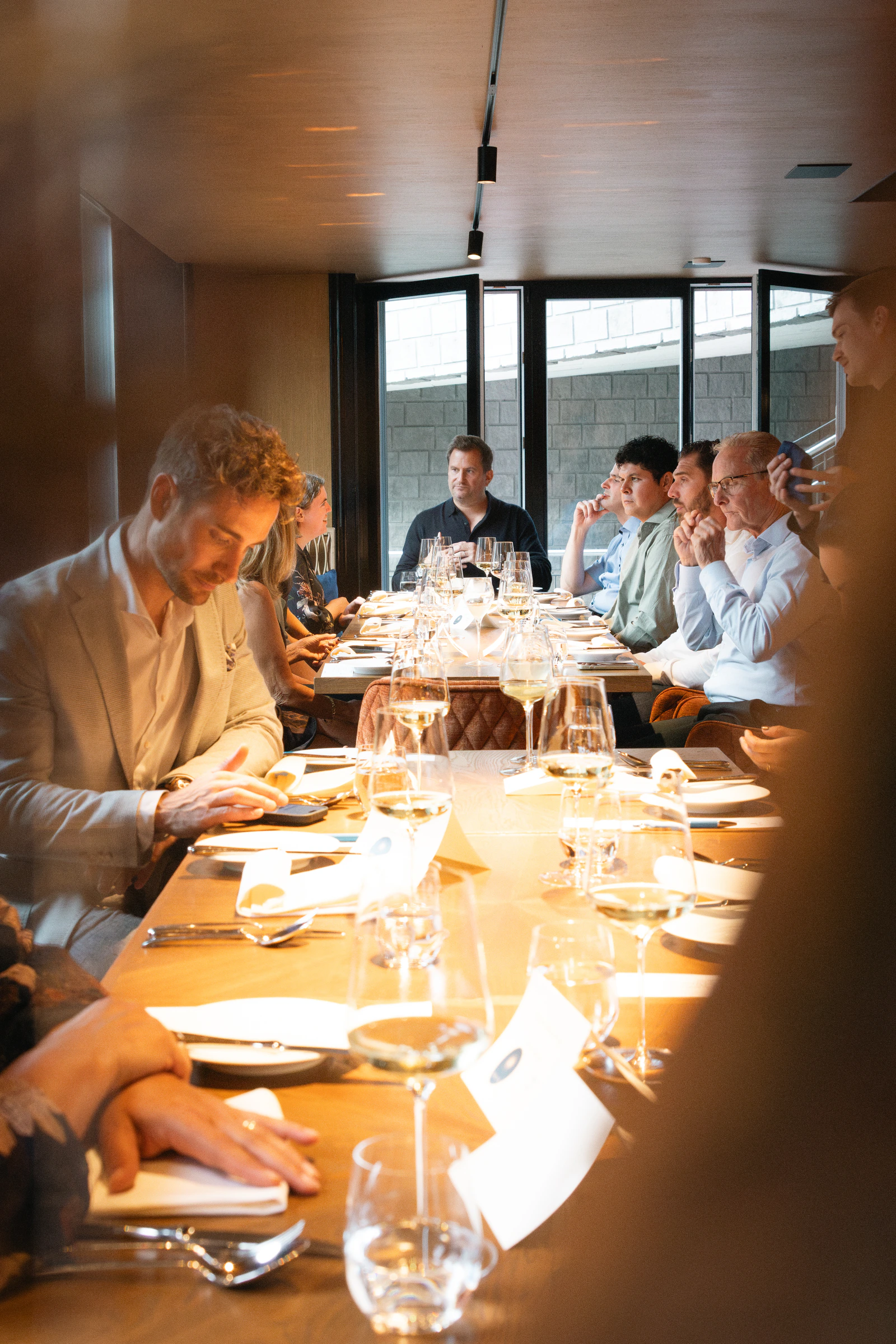 The long table mid-service, glasses down its length