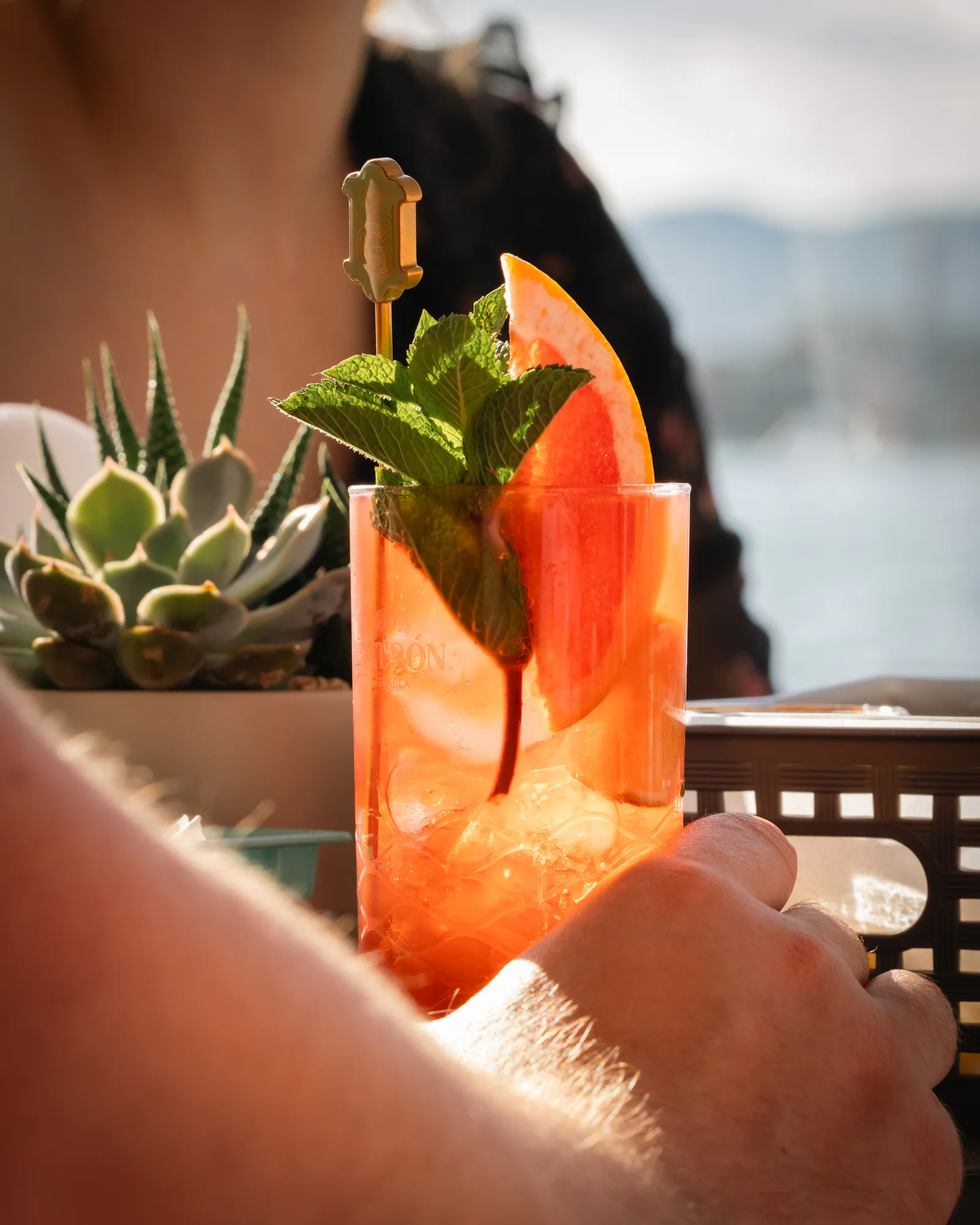 A garnished cocktail held up against the water