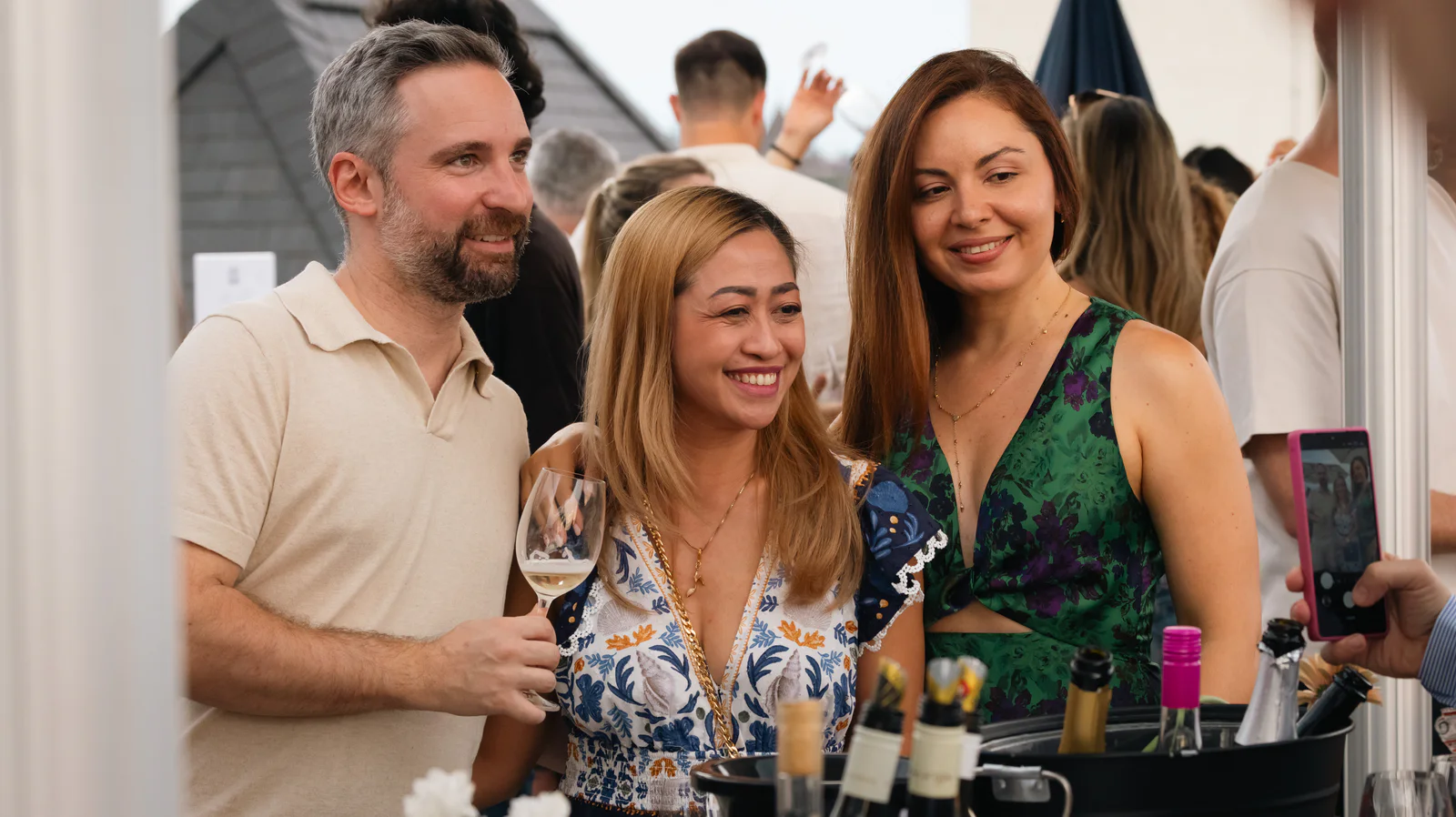 Three guests laughing together with wine glasses at the tasting counter