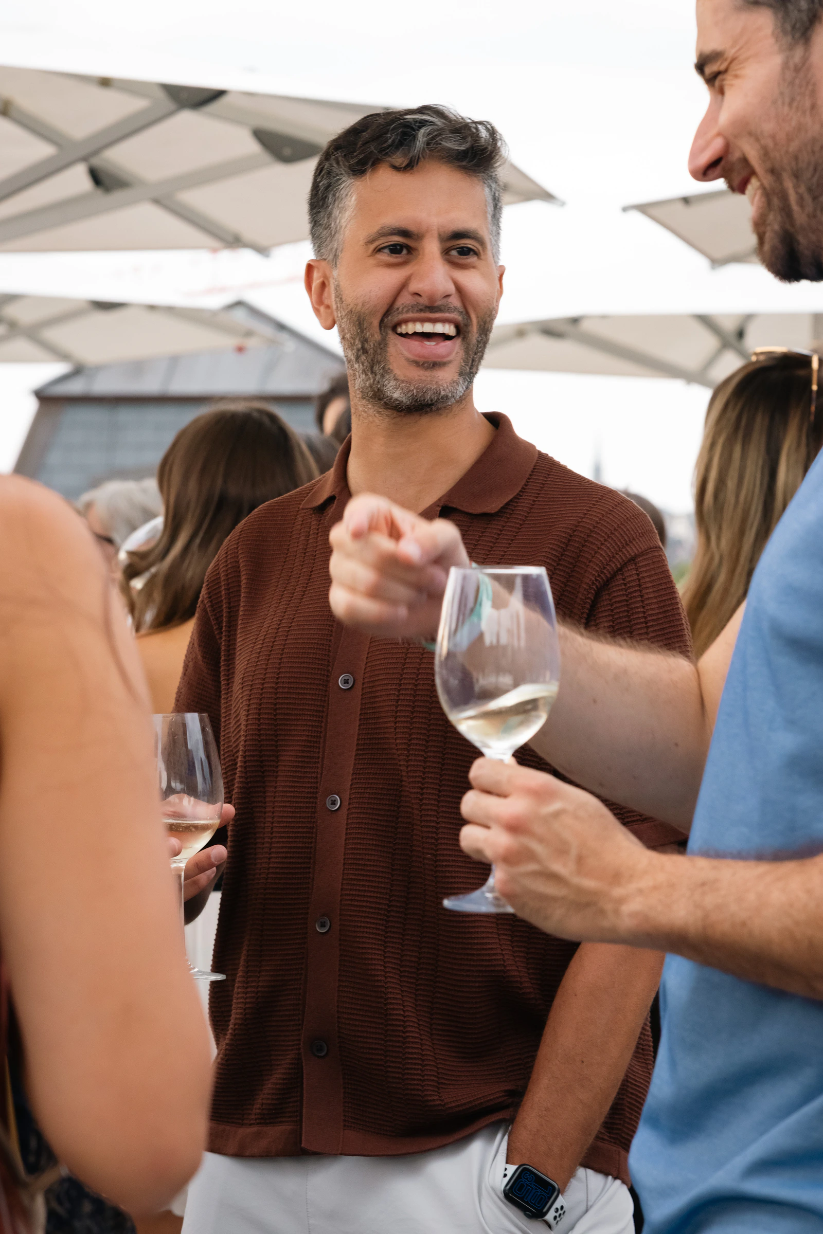 A guest raising a glass of white wine to someone off-frame